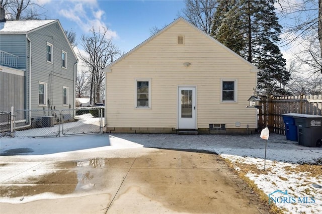 snow covered house featuring a gate, fence, and a patio