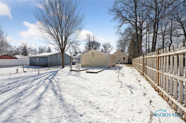 yard layered in snow featuring a fenced backyard and an outdoor structure