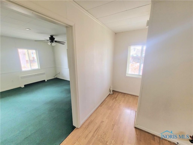 spare room featuring a ceiling fan, baseboards, radiator heating unit, and wood finished floors