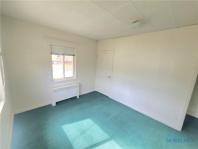 empty room featuring baseboards, carpet, and radiator