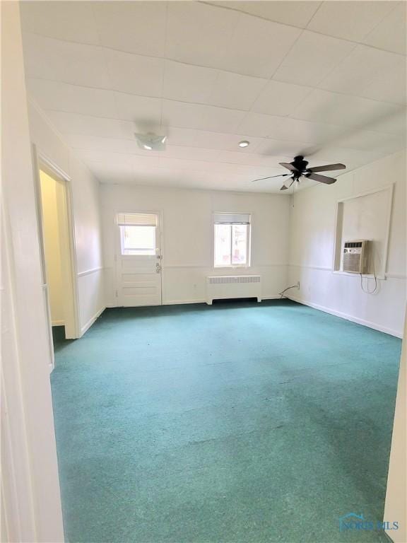 unfurnished room featuring baseboards, carpet flooring, ceiling fan, and radiator heating unit