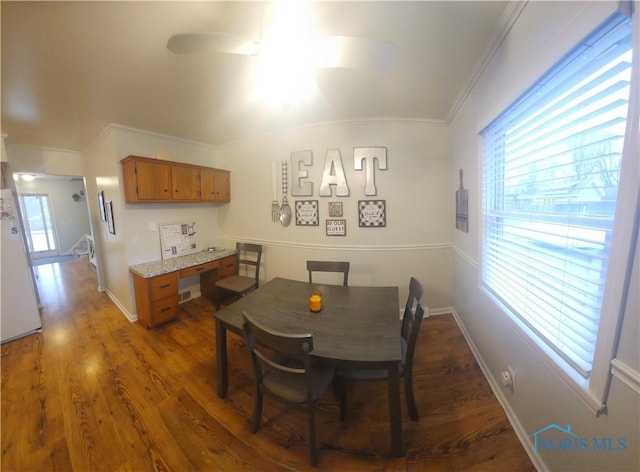 dining space with dark wood-style floors, plenty of natural light, and crown molding