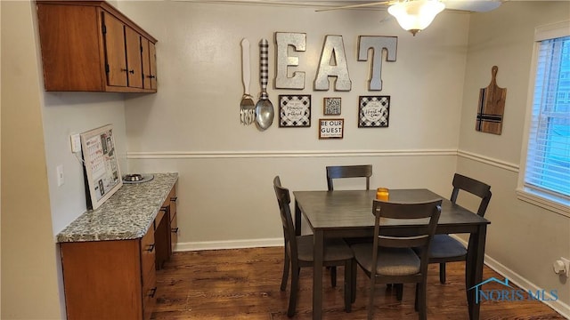 dining room with dark wood-style flooring, ceiling fan, and baseboards