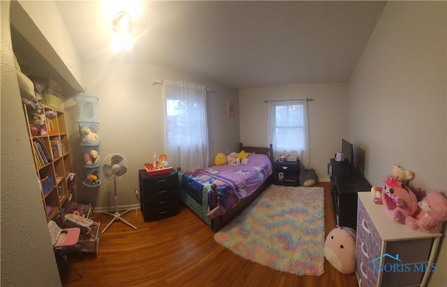 bedroom with vaulted ceiling, multiple windows, and wood finished floors