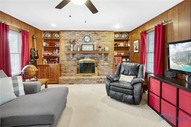 living area featuring built in shelves, a brick fireplace, light colored carpet, and wood walls