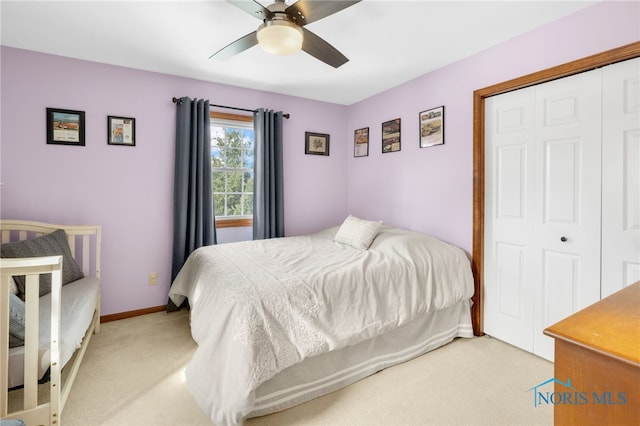 bedroom with baseboards, ceiling fan, a closet, and light colored carpet