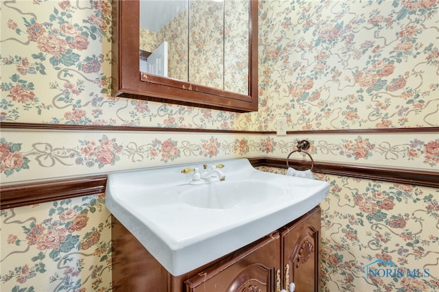 bathroom with a wainscoted wall, vanity, and wallpapered walls