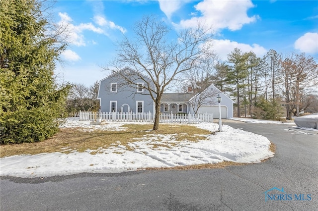 view of front of house with a fenced front yard, a chimney, an attached garage, and aphalt driveway