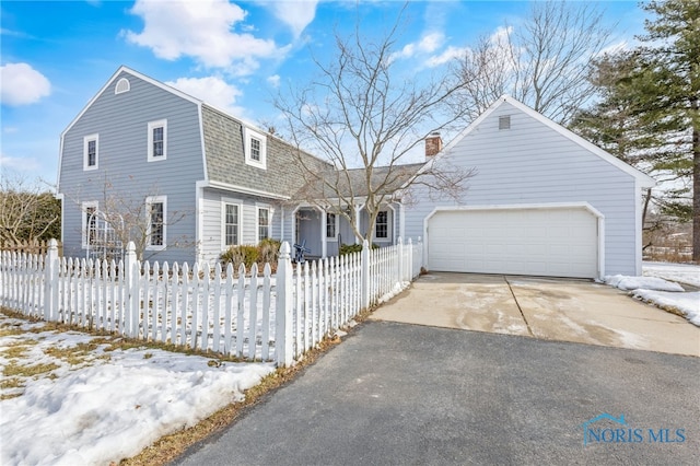 dutch colonial featuring aphalt driveway, a shingled roof, a fenced front yard, and a garage