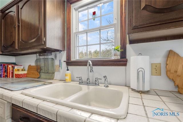 kitchen with a wealth of natural light, a sink, tile countertops, and dark brown cabinets