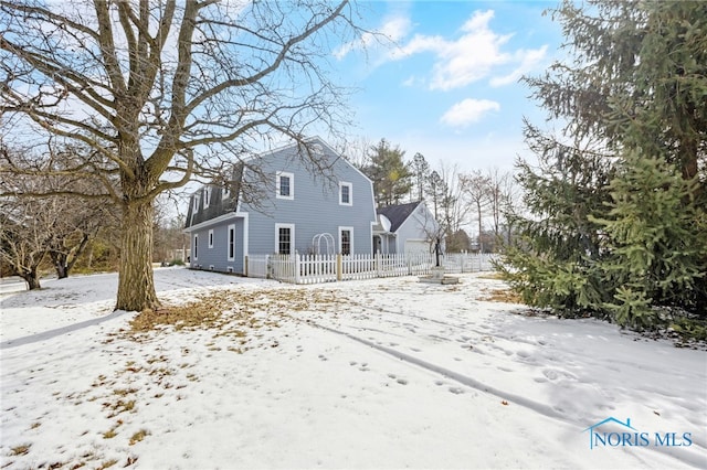 snow covered rear of property featuring fence