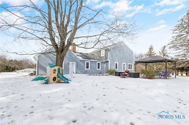 snow covered house featuring a chimney and a gazebo