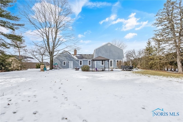 snow covered property featuring a gazebo, a chimney, and a gambrel roof