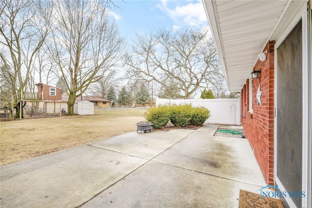 view of patio / terrace featuring an outdoor structure, a fire pit, a storage shed, and fence