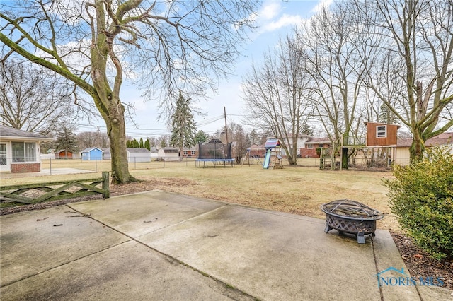 view of yard with an outdoor fire pit, a patio, a trampoline, fence, and a playground