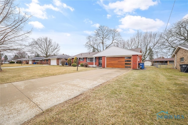 view of front of house featuring a garage, a front yard, concrete driveway, and brick siding