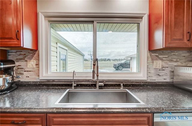 kitchen with stainless steel dishwasher, a sink, and decorative backsplash