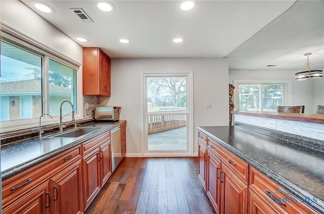 kitchen featuring visible vents, dishwasher, backsplash, dark wood-style flooring, and a sink