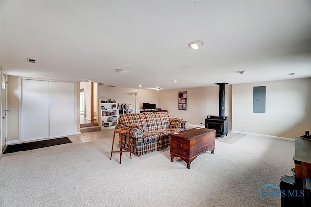 living area featuring light colored carpet, visible vents, baseboards, electric panel, and a wood stove