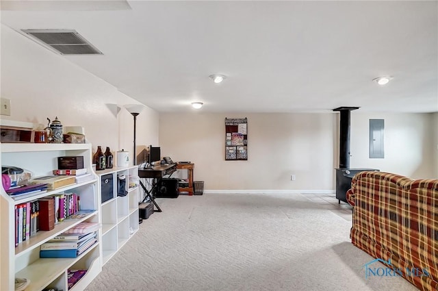 living area featuring electric panel, visible vents, baseboards, a wood stove, and carpet