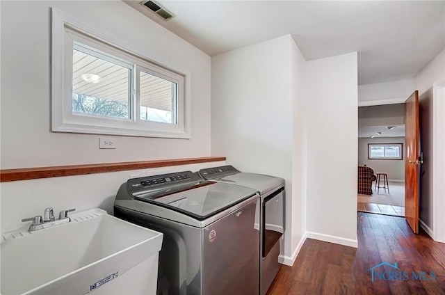 laundry area with laundry area, visible vents, dark wood-style flooring, washer and dryer, and a sink