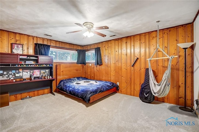 carpeted bedroom featuring wood walls and visible vents