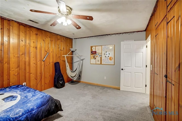 bedroom featuring carpet floors, visible vents, ceiling fan, and wooden walls