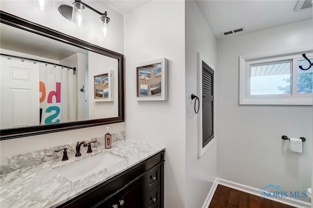 bathroom featuring baseboards, visible vents, wood finished floors, and vanity