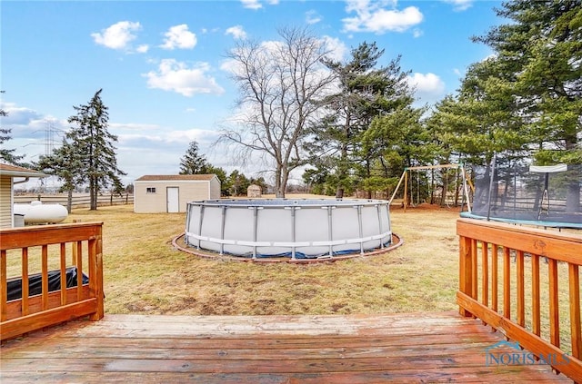 wooden deck featuring an outbuilding, a storage shed, fence, a lawn, and an outdoor pool