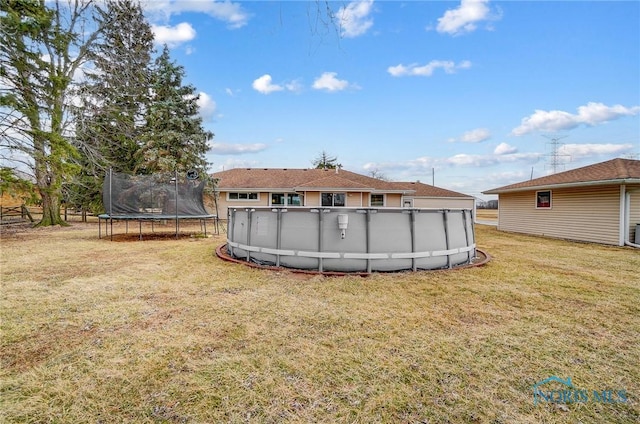 back of house with a trampoline, an outdoor pool, and a yard