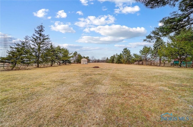 view of yard featuring an outbuilding, fence, and a shed