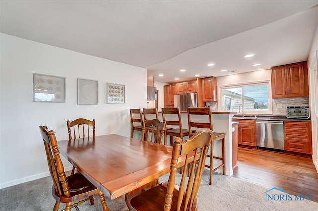 dining area featuring baseboards, light wood-style floors, and recessed lighting