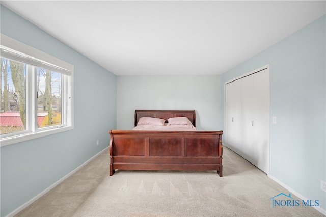 bedroom featuring a closet, light colored carpet, and baseboards