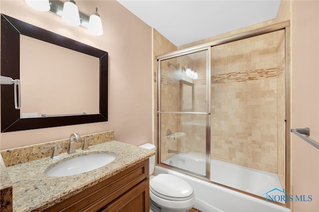 bathroom featuring enclosed tub / shower combo, vanity, and toilet