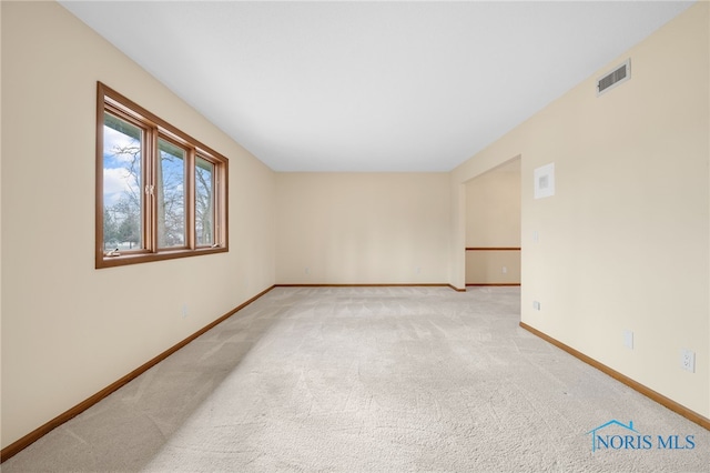 spare room featuring light carpet, baseboards, and visible vents