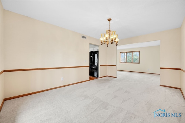 spare room with light colored carpet, visible vents, a notable chandelier, and baseboards