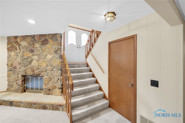 stairway featuring carpet floors and a fireplace