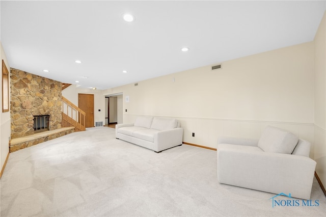 carpeted living area with recessed lighting, wainscoting, visible vents, and a stone fireplace