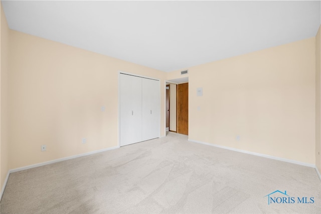 unfurnished bedroom with baseboards, a closet, visible vents, and light colored carpet