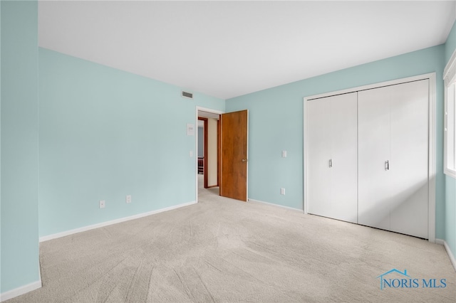 unfurnished bedroom featuring baseboards, carpet, visible vents, and a closet