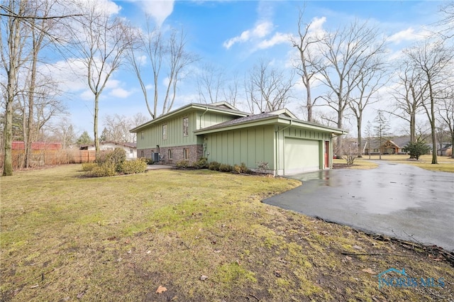 view of property exterior with driveway, a garage, fence, and a lawn