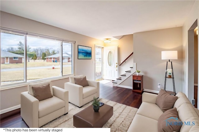 living room featuring stairs, baseboards, and wood finished floors