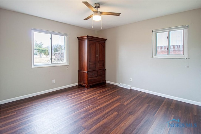 unfurnished bedroom featuring dark wood-type flooring, visible vents, ceiling fan, and baseboards