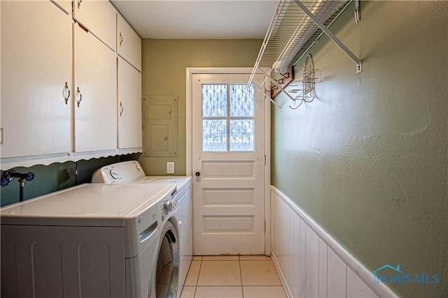 laundry room featuring wainscoting, cabinet space, washing machine and clothes dryer, and light tile patterned floors