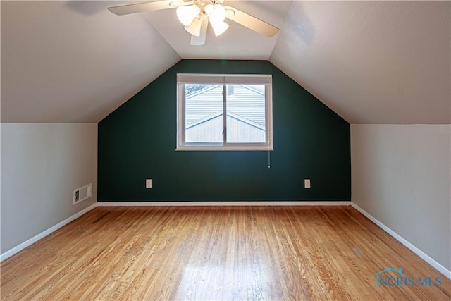 additional living space with ceiling fan, visible vents, baseboards, vaulted ceiling, and light wood-type flooring