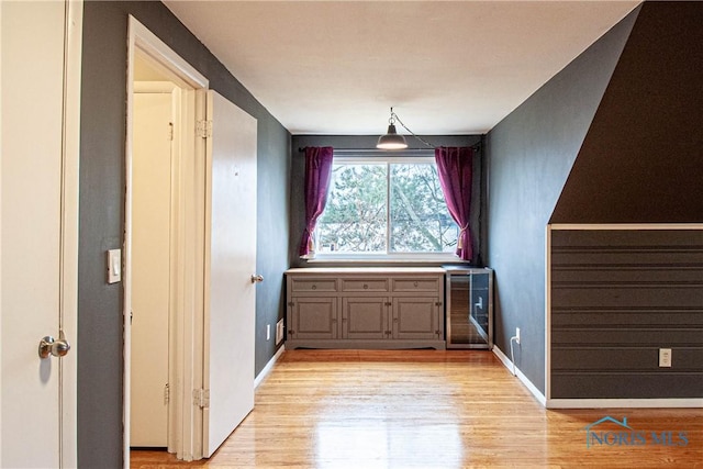 interior space featuring beverage cooler, light wood-style flooring, and baseboards