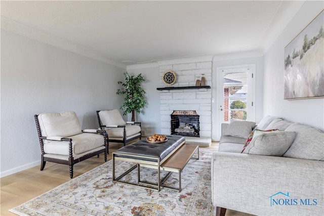 living room featuring a large fireplace, crown molding, wood finished floors, and baseboards