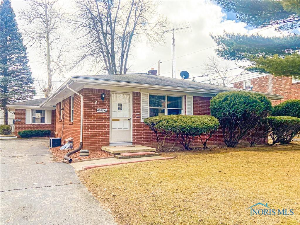 view of front facade with driveway, a front yard, and brick siding