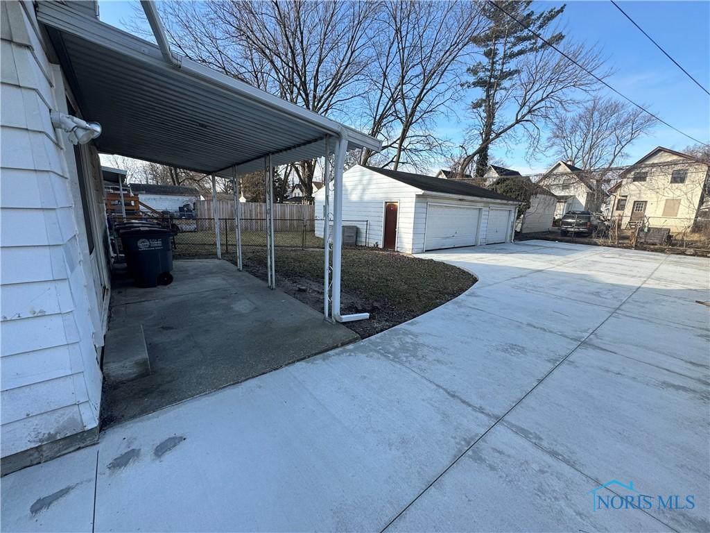 view of home's exterior featuring a detached garage, fence, and an outdoor structure