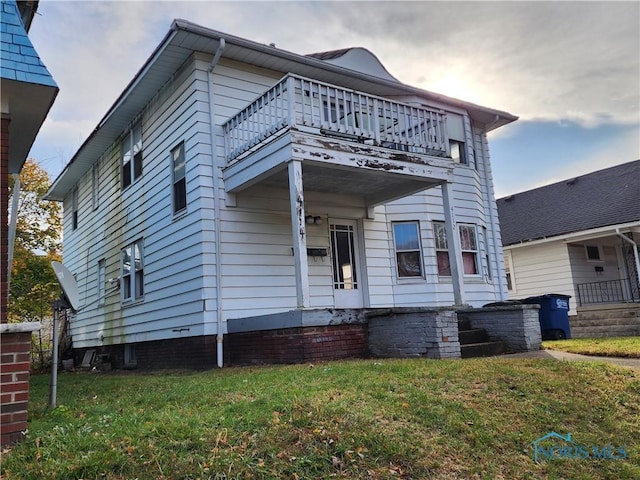 view of front of home with a front yard and a balcony